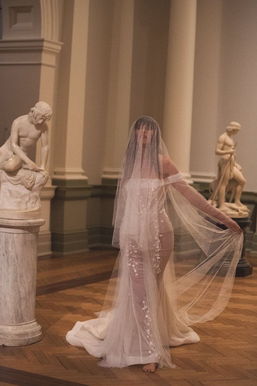Bruid in museum in kanten trouwjurk met lange mouwen