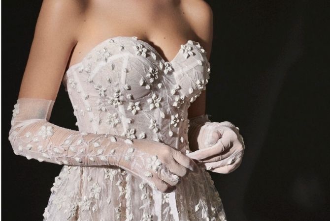 Close up foto van strapless trouwjurk met 3D kant en handschoenen