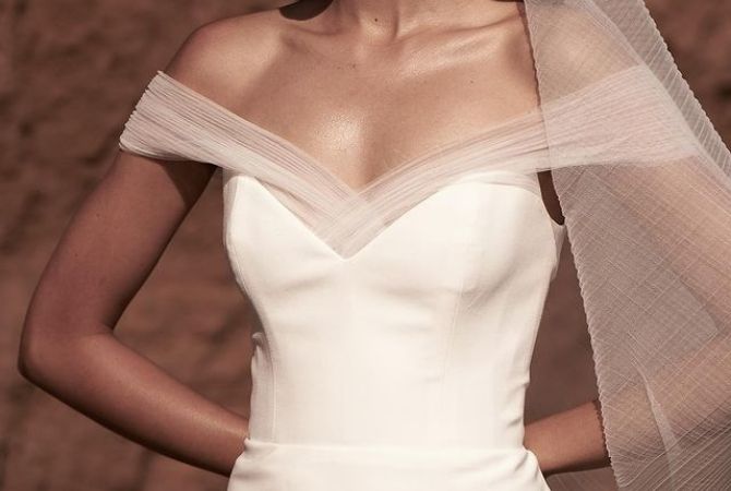 close up foto van top van moderne strakke trouwjurk met off shoulder tulle mouwen