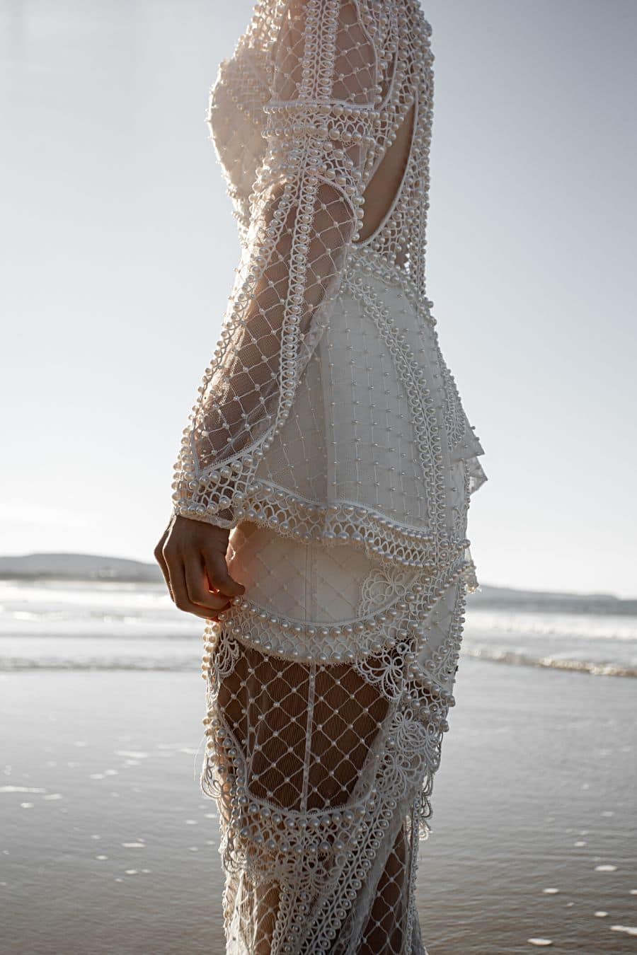 close up photo of pearl wedding dress on the beach