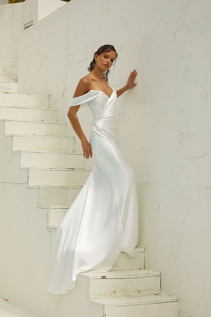 Bride walking up stairs in satin fitted wedding dress with off shoulder neckline
