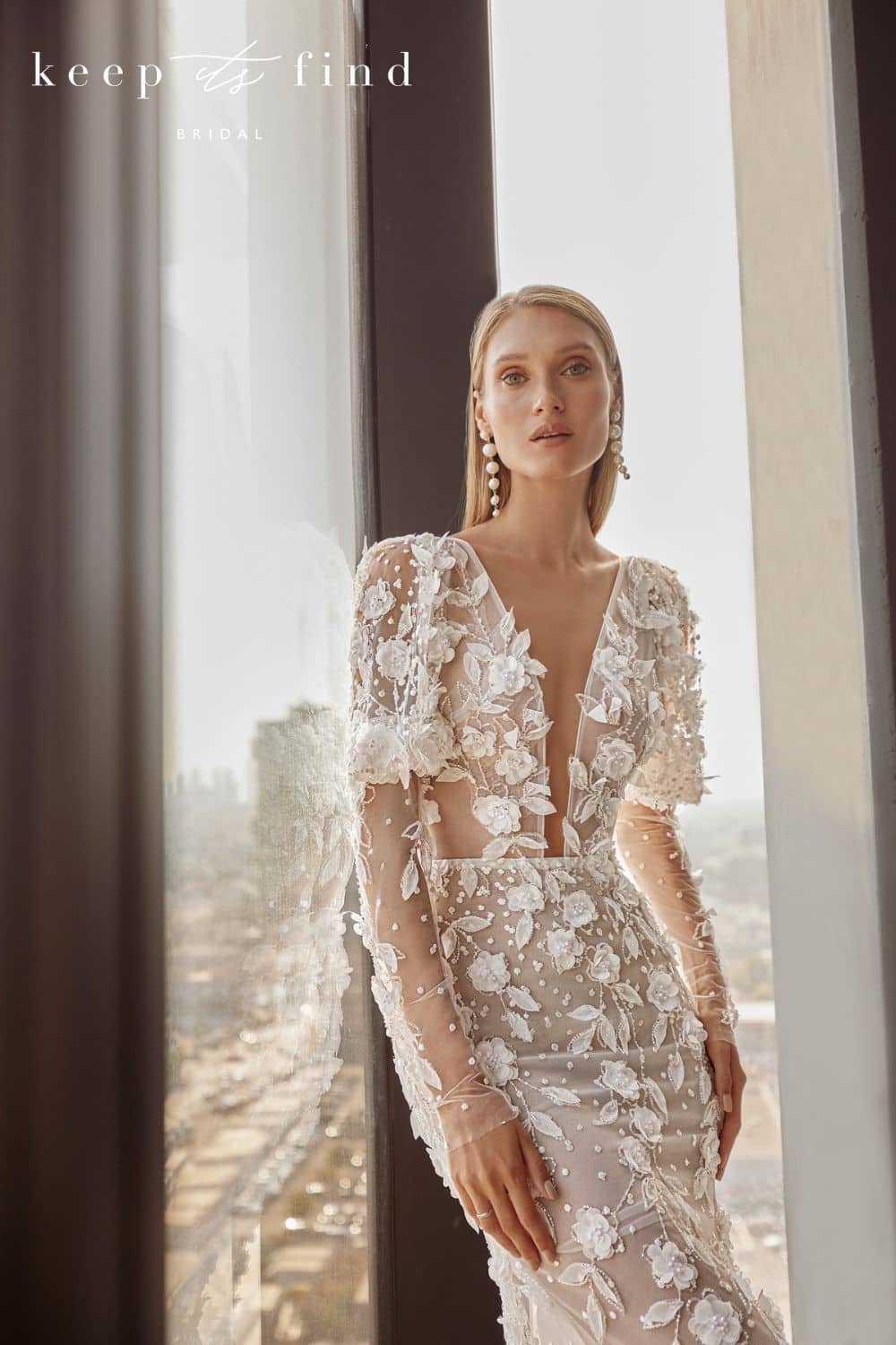 Bride leaning on windown in one-of-a-kind lace wedding dress with long sleeves