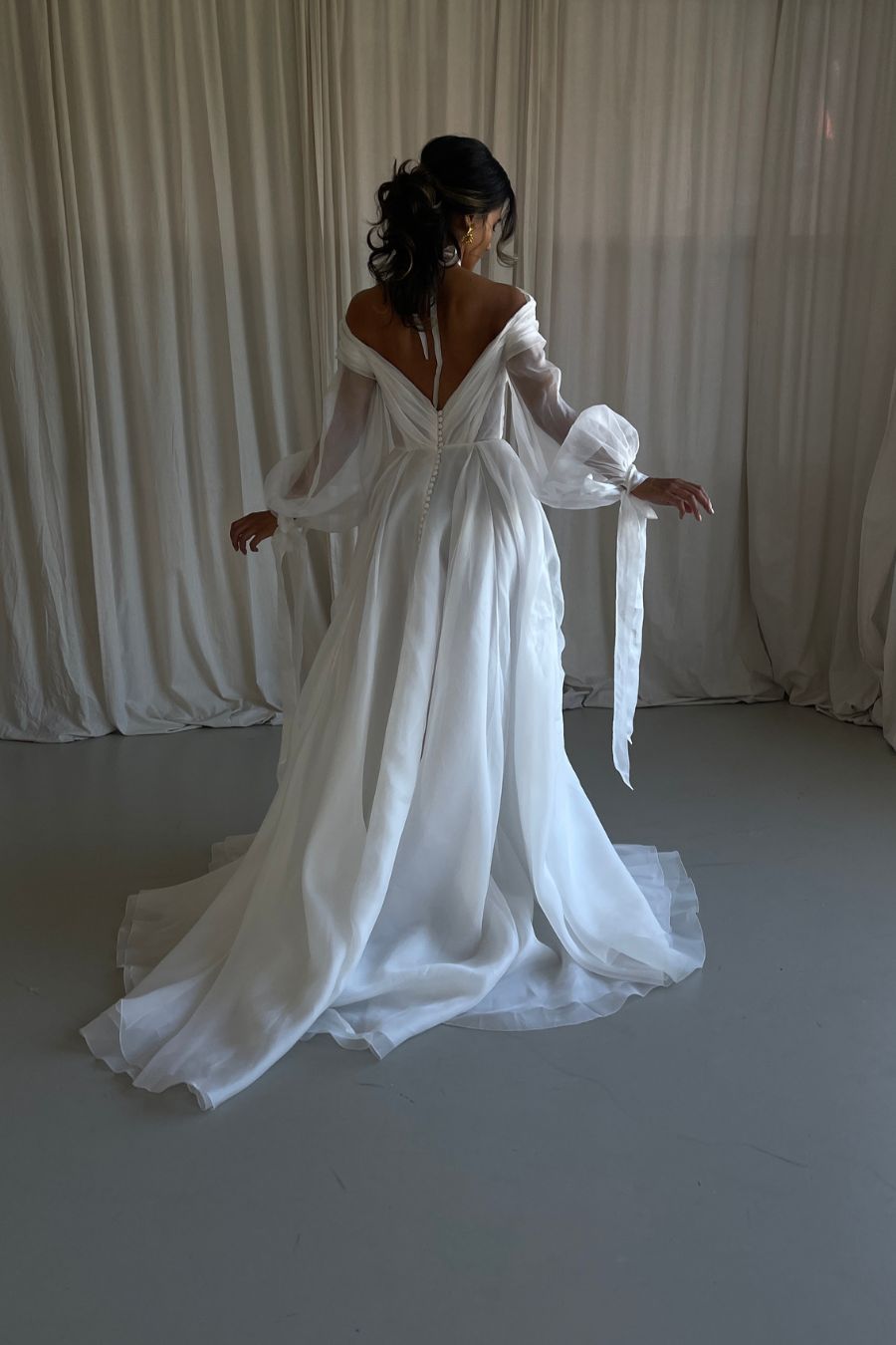 photo of bride walking in aline wedding dress with long sleeves and low back