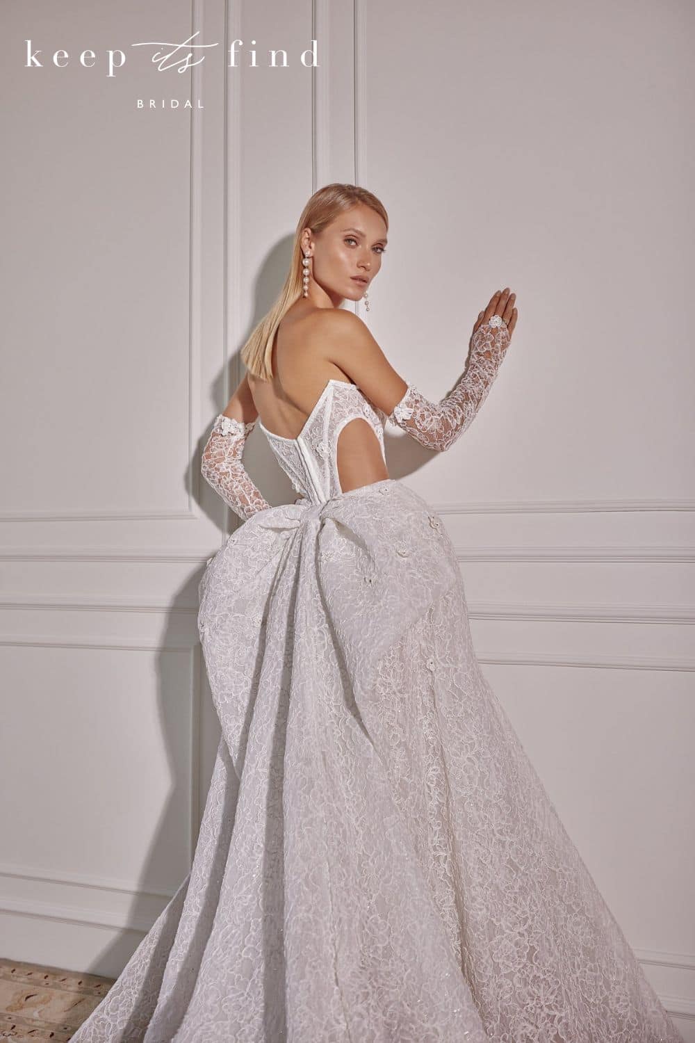 Bride looking over shoulder in strapless lace wedding dress with detachable skirt with bow details